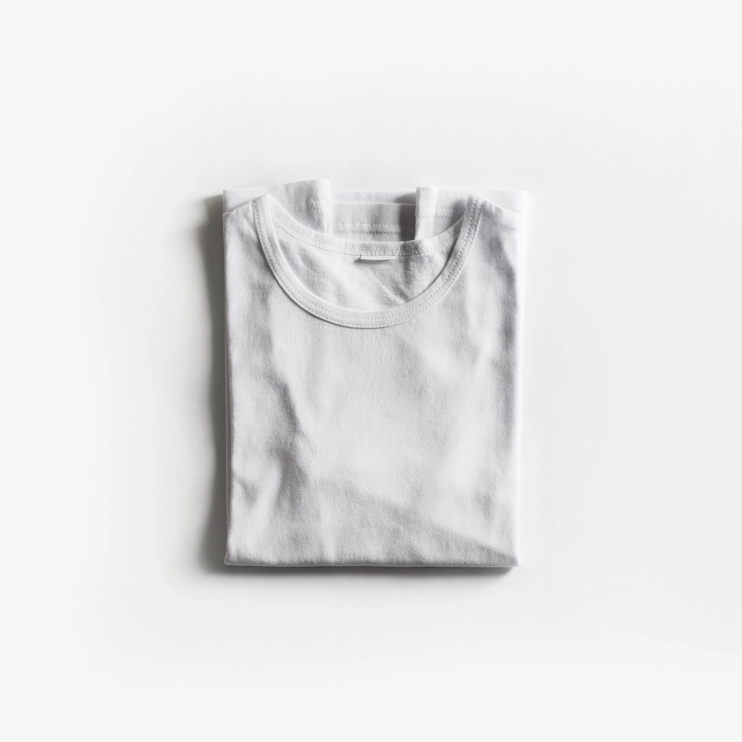 Folded white t-shirt flat lay on a white background.